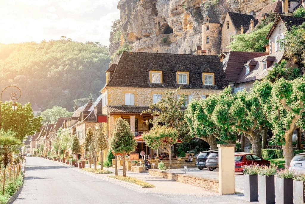 La Roque-Gageac village with yellow stone houses located against a cliff on a sunny day in the Dordogne Valley