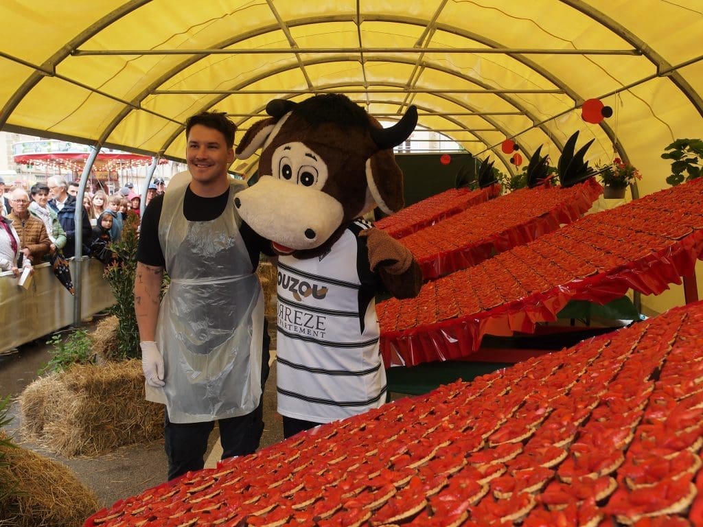 Volunteer and mascot at the giant strawberry tart during the Fête de la Fraise in Beaulieu-sur-Dordogne