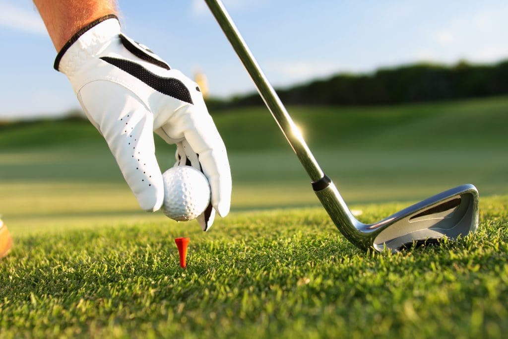Close-up of a golfer's hand placing a golf ball on a tee