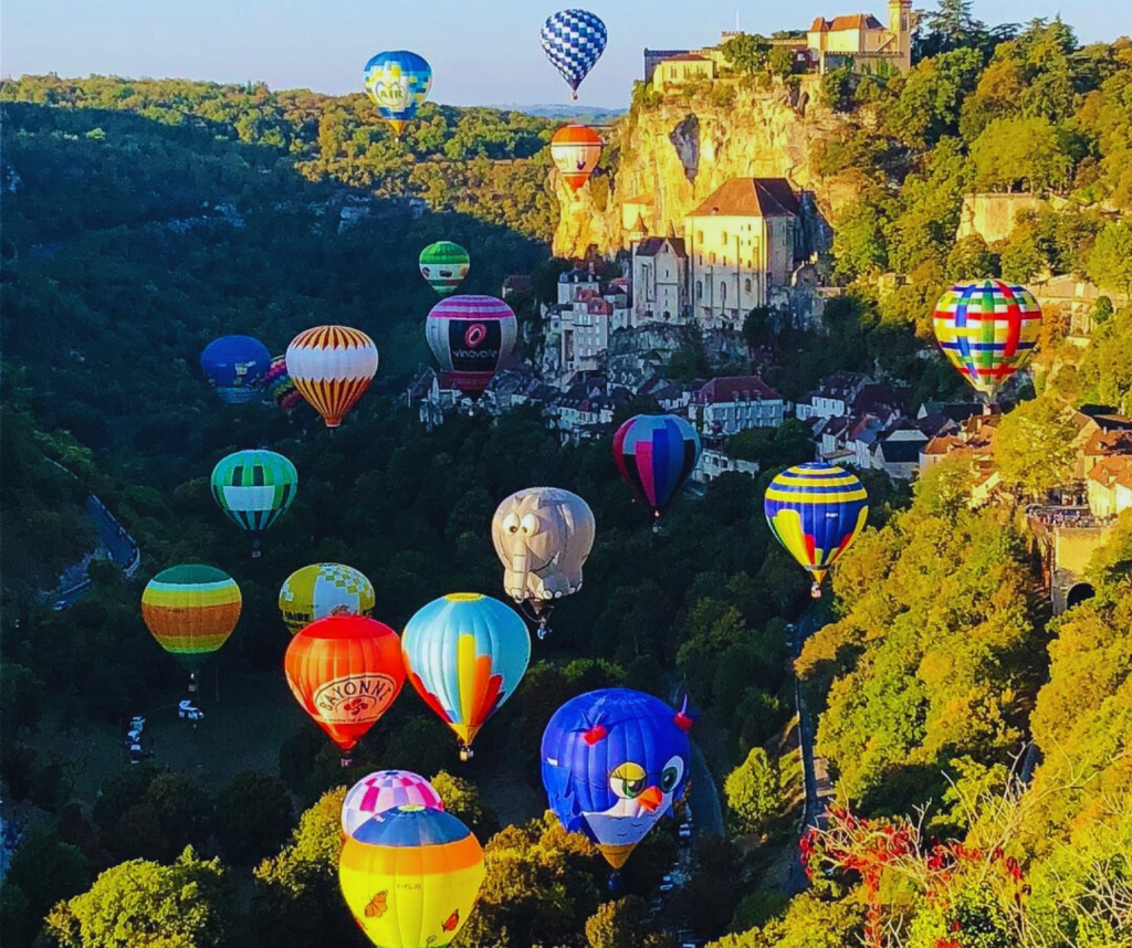 erial view of the Dordogne Valley with multiple hot air balloons.