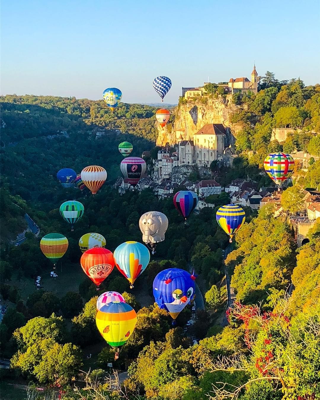 Colorful hot air balloons floating above the cliffs of Rocamadour.