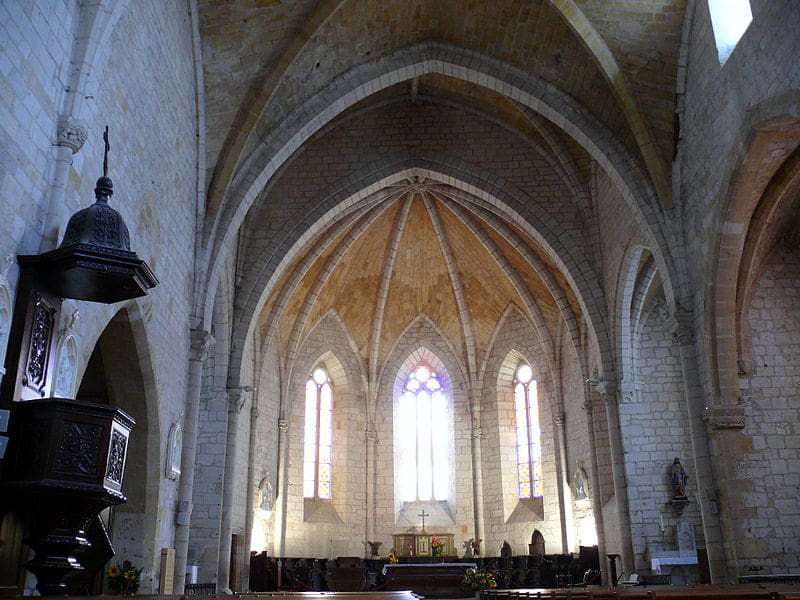 The interior of a church with arched ceilings, stained glass windows, and wooden pews
