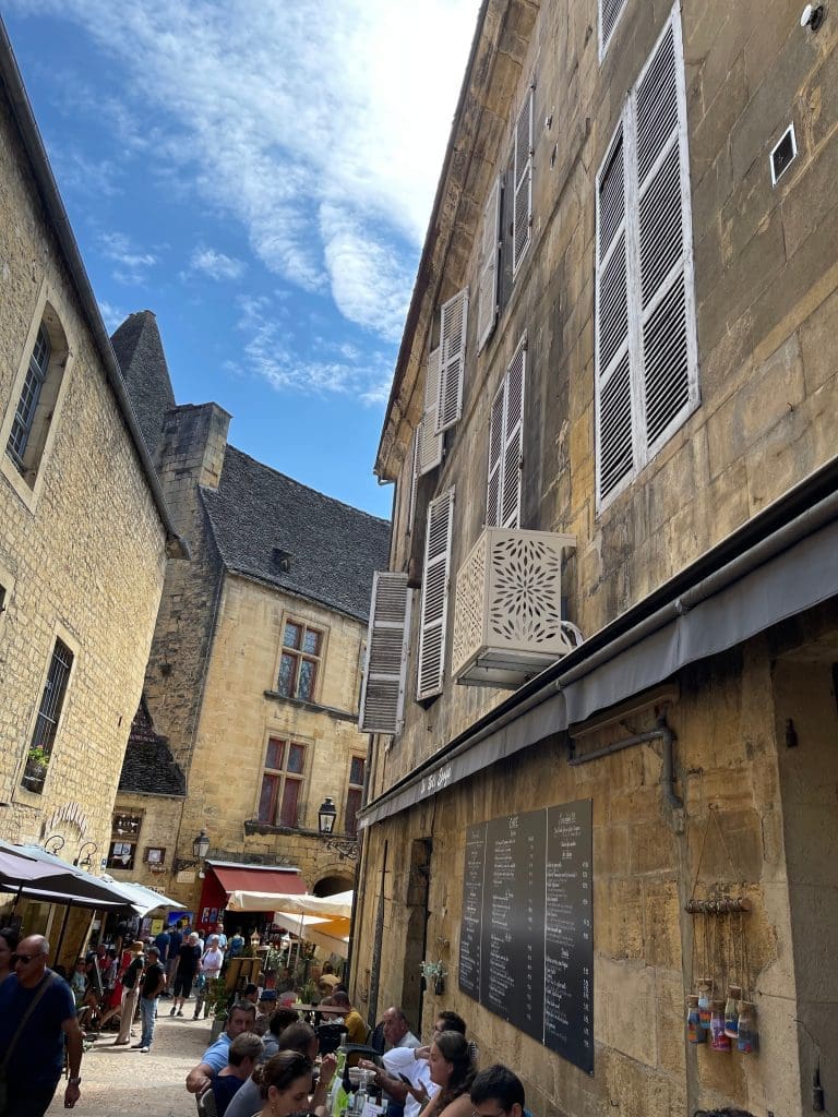 Outdoor seating at La Belle Époque restaurant in Sarlat, surrounded by historic golden stone buildings.