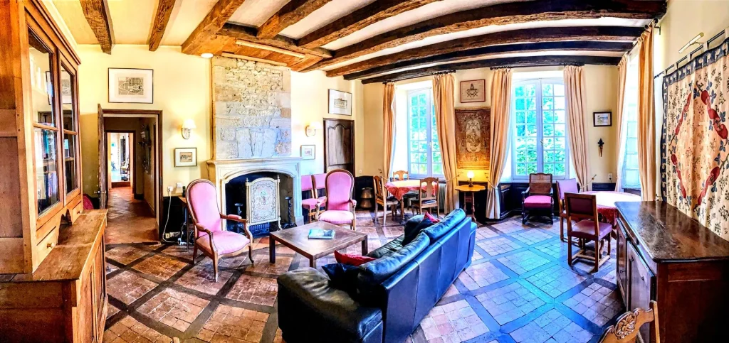 Elegant and cozy interior of La Lanterne Chambres d'Hôtes, a top-rated B&B in Dordogne, featuring rustic wooden beams, a fireplace, and vintage-style furniture.